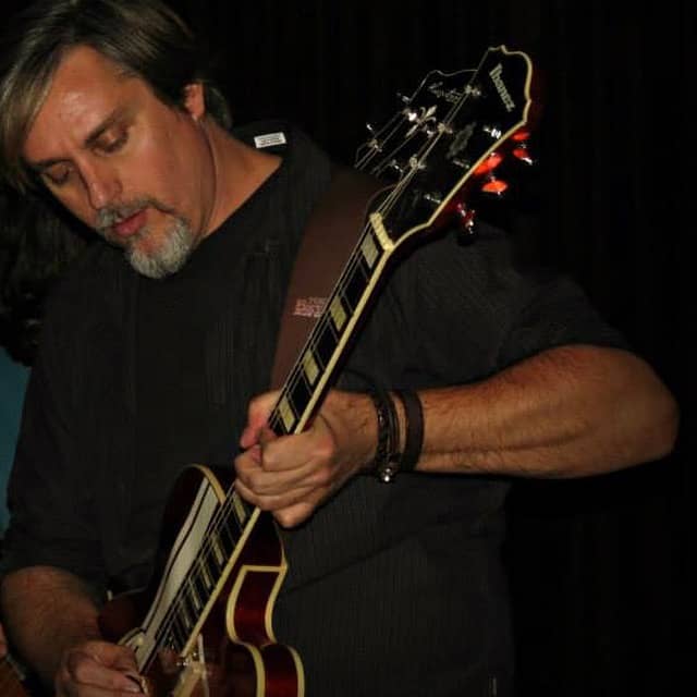 Man playing a semi-hollow body Ibanez electric guitar